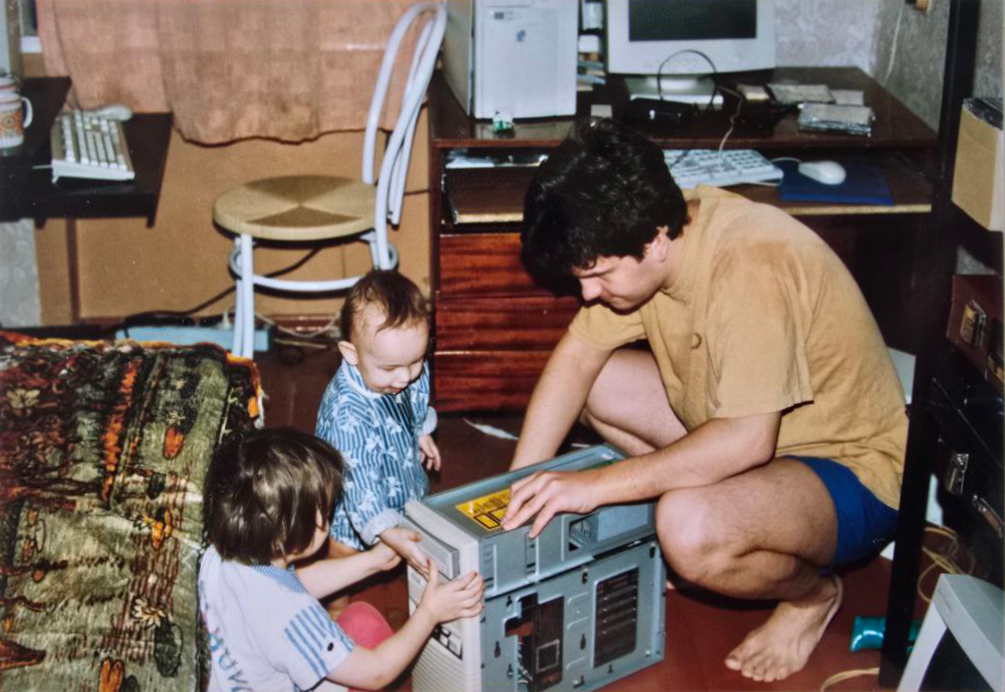 Family photograph: a father and two children gathered around an open computer.